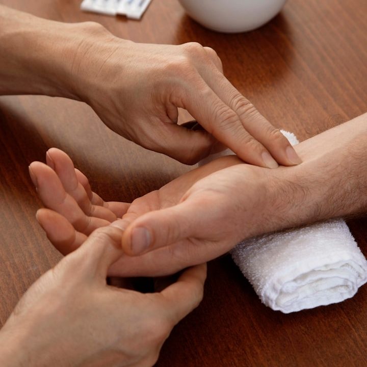 Puls Eine Hand überprüft den Puls einer anderen Hand auf einer Tischoberfläche.